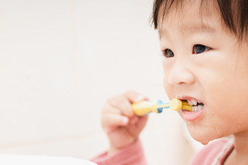 Sweet Asian child little girl brushing her teeth in bathroom