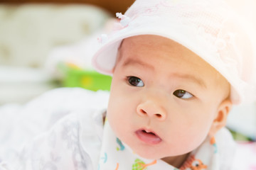 sweet asian baby laying  on bed at home with gradient