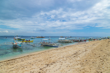 BALICASAG / PHILIPPINES - OCTOBER 30, 2018: Tropical background view from Balicasag island with traditional boats (bancas), blue sky and turquoise sea water, Travel vacation at Philippines.