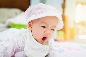 sweet asian baby laying  on bed at home with gradient