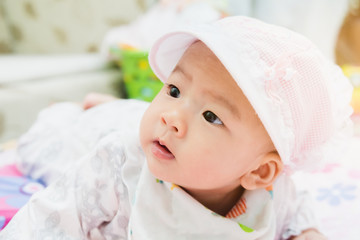 sweet asian baby laying  on bed at home with gradient