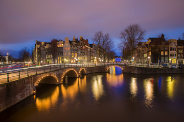 View on romantic canal Leidsegracht in Amsterdam at night with city lights, bridges and reflection on water
