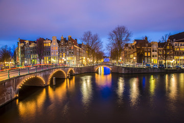View on romantic canal Leidsegracht in Amsterdam at night with city lights, bridges and reflection on water
