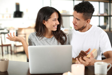 Young couple with laptop and book at home