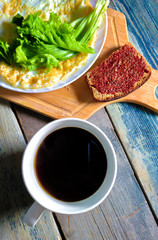 Fried egg in the form of a pancake, wooden cutting board. Breakfast, still life.
