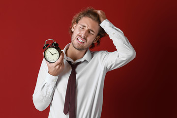 Stressed businessman with alarm clock on color background