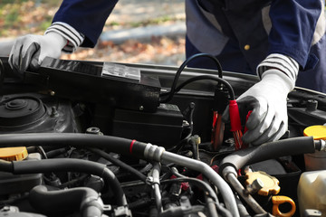 Male mechanic charging a car battery