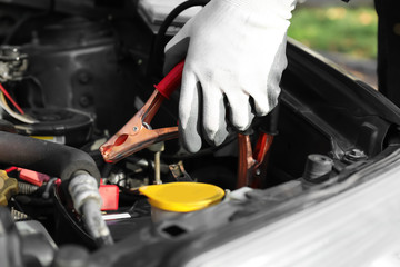 Fototapeta premium Car breakdown and emergency assistance, person connecting jumper cables to a dead car battery