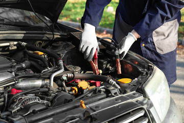 Male mechanic charging a car battery