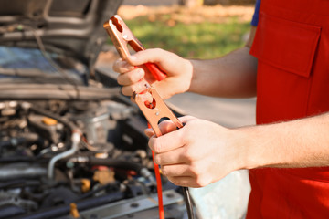 Male mechanic charging a car battery