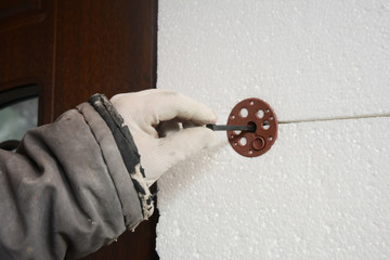 Builder contractor  installing rigid styrofoam insulation board with plastic nail for holding.