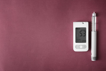 Digital glucometer with syringe on color background. Diabetes control