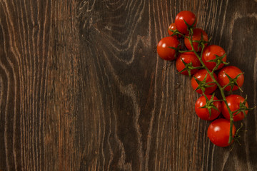 Cherry tomatoes with water drops lie on a brown background.