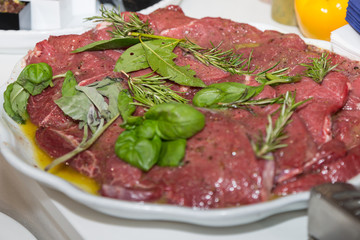 Raw Beef ready to be Cooked and Prepared with Oil, Pepper, Basil, Rosemary and Bay Leaves