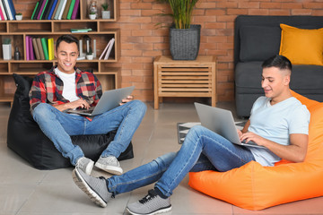 Young men studying with laptops at home