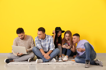 Young students sitting on floor near color wall