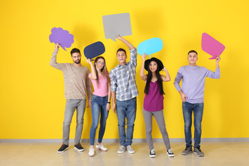 Young people with blank speech bubbles near color wall