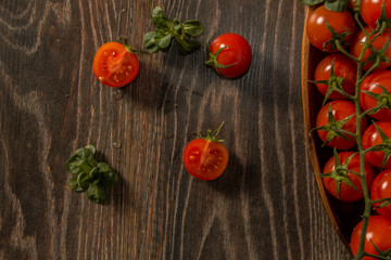 Cherry tomatoes with water drops lie on a brown background.