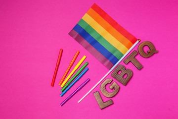Rainbow flag with markers and abbreviation LGBTQ on color background
