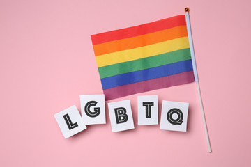 Rainbow flag with abbreviation LGBTQ on color background