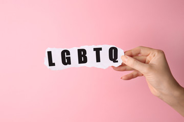 Female hand with abbreviation LGBTQ on color background