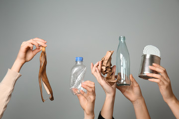 Many hands with different types of garbage on grey background. Ecology concept