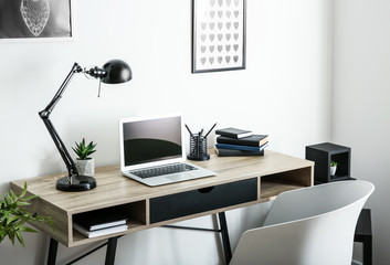 Stylish workplace with laptop in room