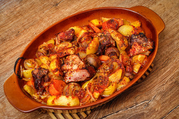 Stew with homemade smoked meat and vegetables in ceramic bowl. Sweet and plain potato, carrot, champignon mushrooms garlic and onion.