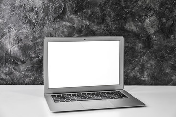Fototapeta premium Modern laptop on table against grey wall
