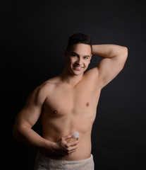 Fototapeta na wymiar Young man with deodorant on dark background