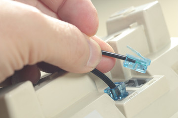 Man is Connecting rj45 jack on telephone data port