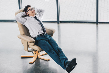 high angle view of young kazakh businessman in eyeglasses resting in chair