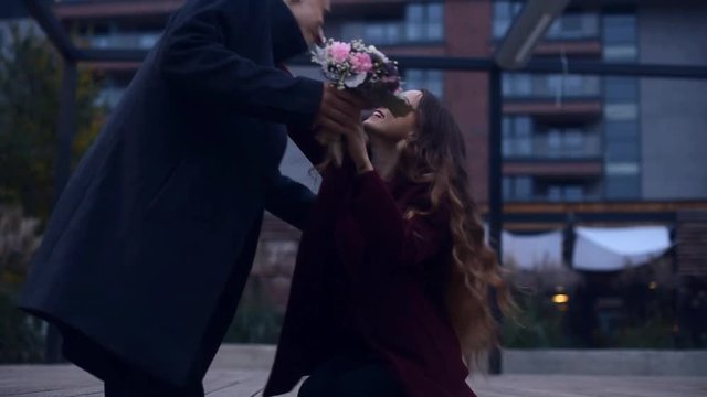 Girl taxting massage at date apps. Couple having first date at the park. Lovely speaking to each other . Boy present to his girl flowers. Girl with cerly hair. Sprong weather, couple at coat.