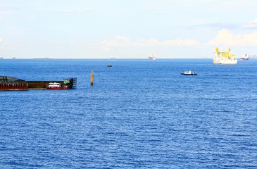 Harbor and boat are carrying cargo on the sea in Singapore. Transportation and Beautiful landscape view of ocean with clear blue sky and cloud background