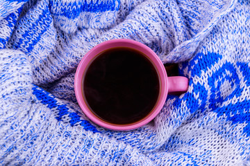 Cup of coffee on cozy knitted sweater