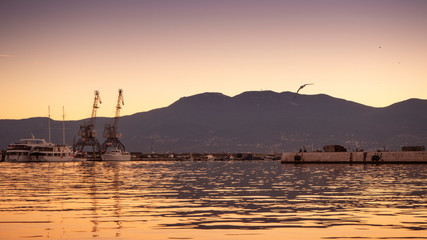 Fototapeta na wymiar Beautiful and Colorful Sunset at the harbor of Rijeka with urban industry and cargo flair in Croatia