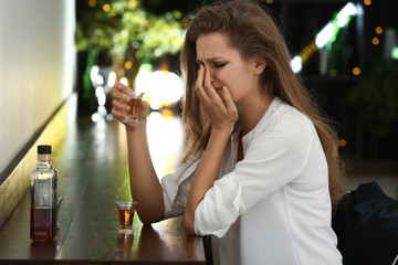 Depressed woman drinking alcohol in pub