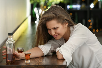 Depressed woman drinking alcohol in pub