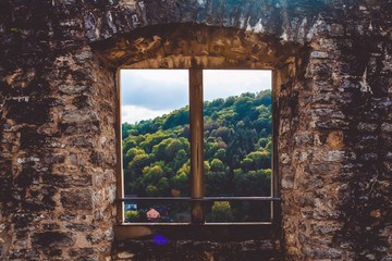 Ancient fortress in Germany. A window with a wooden sun blind from the castle on beautiful view with hills and forests. Summer. Tourist place.
