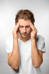 Naklejka premium Young man suffering from headache on light background