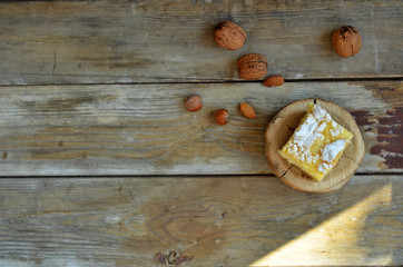 Piece of apple pie sprinkled with powdered sugar on a wooden background