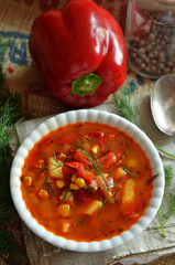 Pepper and tomato soup with potatoes in a white bowl