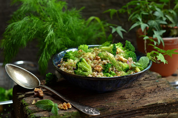 Salad with buckwheat and broccoli in a blue bowl on a wooden background