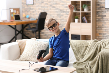 Cute boy playing video game at home