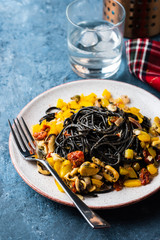 Black pasta with seafood, anchovies, tomatoes and bell peppers.