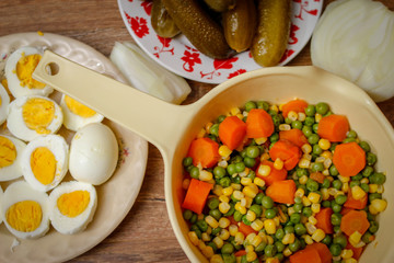 Cooked vegetables, boiled eggs and pickles. Ready components for russian salad, on vintage wooden table.