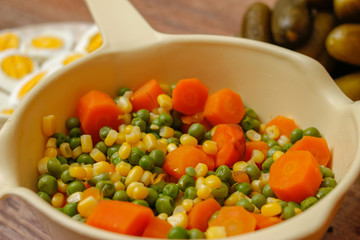 Cooked vegetables, boiled eggs and pickles. Ready components for russian salad, on vintage wooden table.