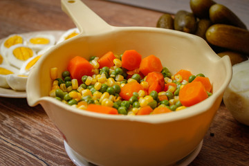 Cooked vegetables, boiled eggs and pickles. Ready components for russian salad, on vintage wooden table.
