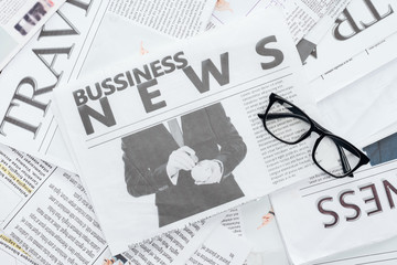 top view of business newspapers and eyeglasses on surface