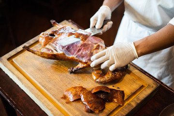 The chef is cutting the duck skin from the Beijing duck with a very sharp knife at a famous Chinese restaurant.